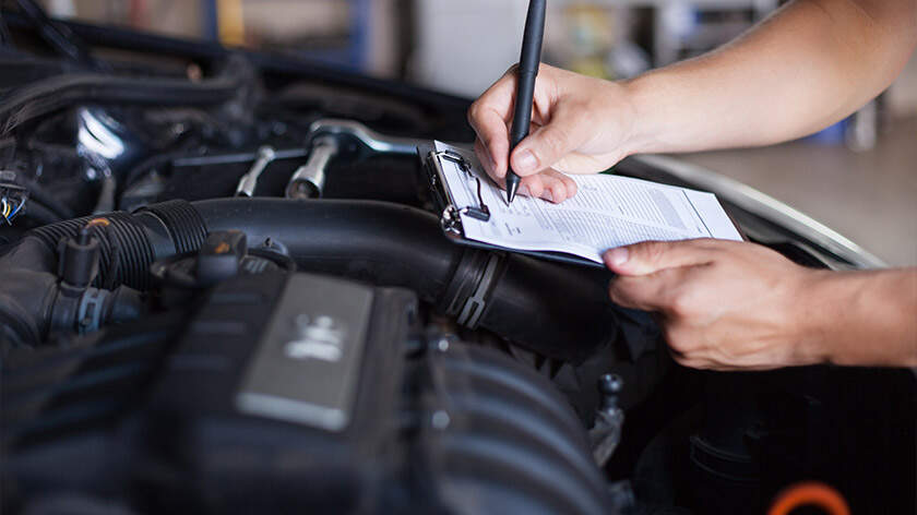 Mechanic is checking the inspection list in front of a open hood